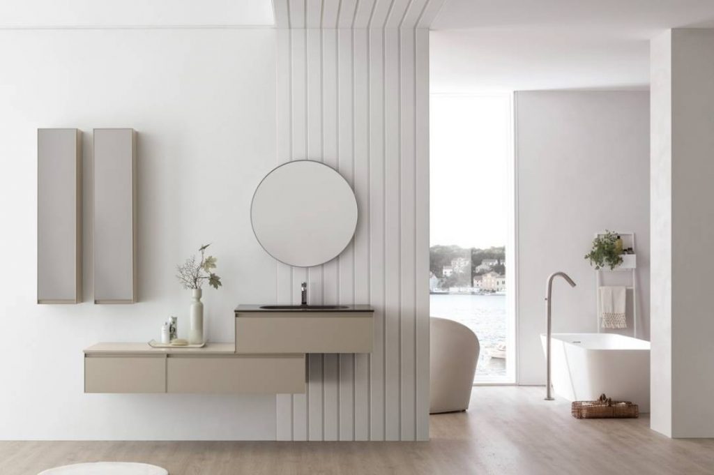 baño minimalista con espejo redondo y lavabo suspendido.
