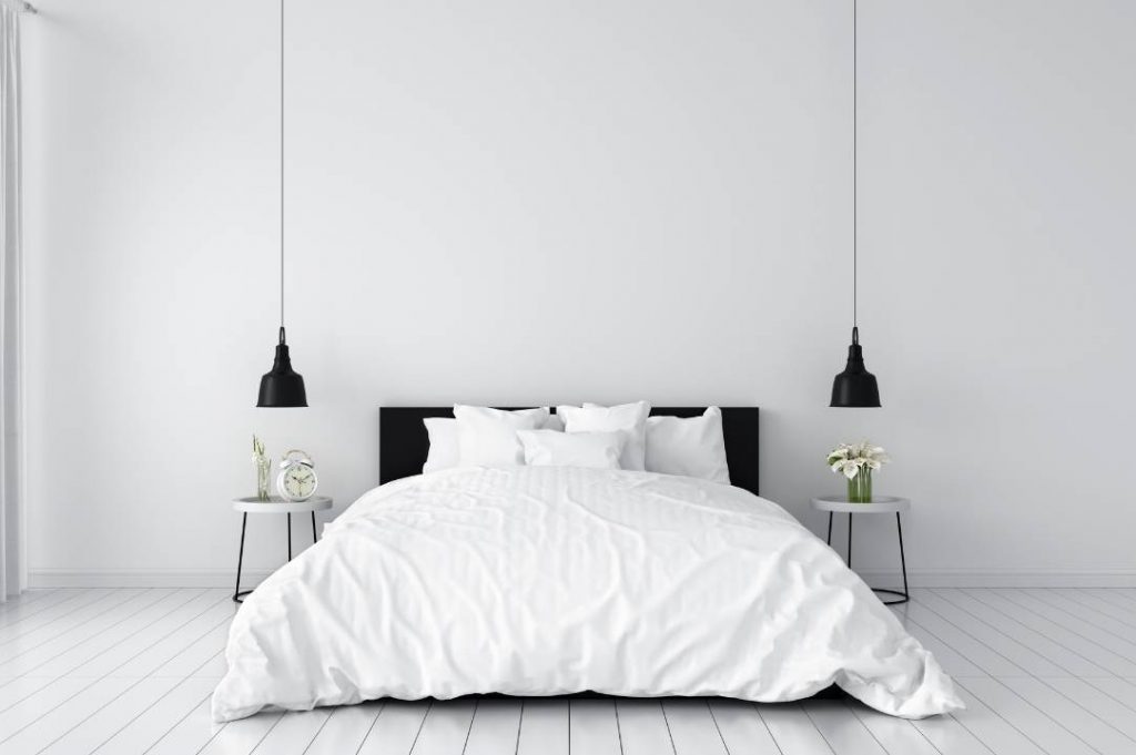 Dormitorio de estilo minimalista con lámpara colgante negra.